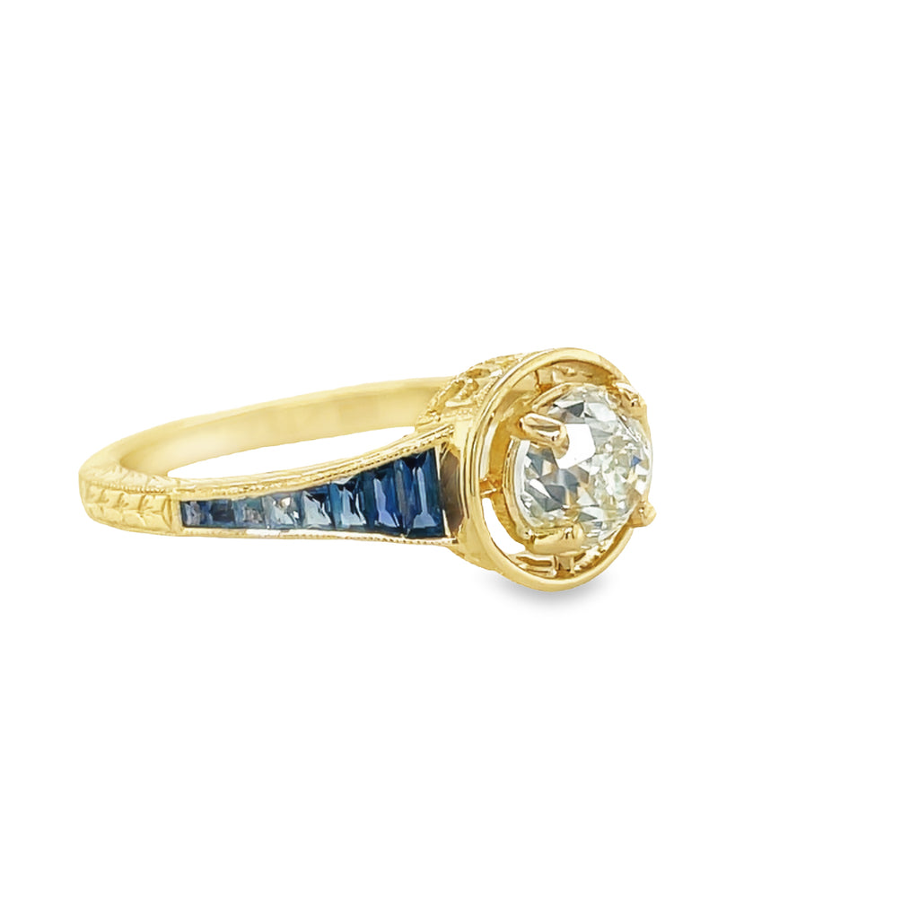 This unique Art Deco Solitaire Diamond & Sapphire Ring is perfect for those seeking an enchanting statement piece. Showcasing a sparkling 0.90 carat diamond, surrounded by a timeless pattern of 0.50 carats of deep blue antique-cut sapphires, all set in 14k yellow gold. A truly eye-catching piece.