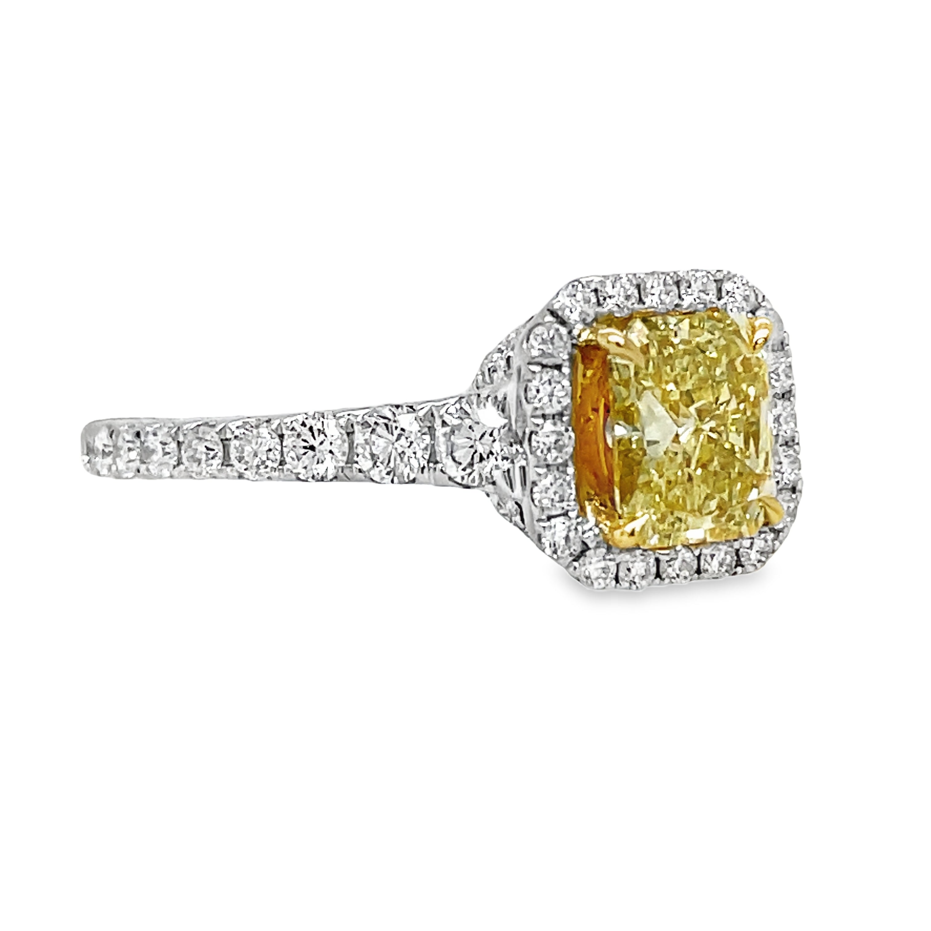 Indulge in the exquisite beauty of our custom-made Fancy Yellow Diamond Radiant Engagement Ring. Crafted from 18k white gold, this sophisticated ring features a stunning 1.10 carat radiant cut diamond surrounded by a 1.00 carat diamond halo and along the shank. The diamonds are set inside the ring, adding to its exclusive design. Elevate your engagement with this luxurious piece.