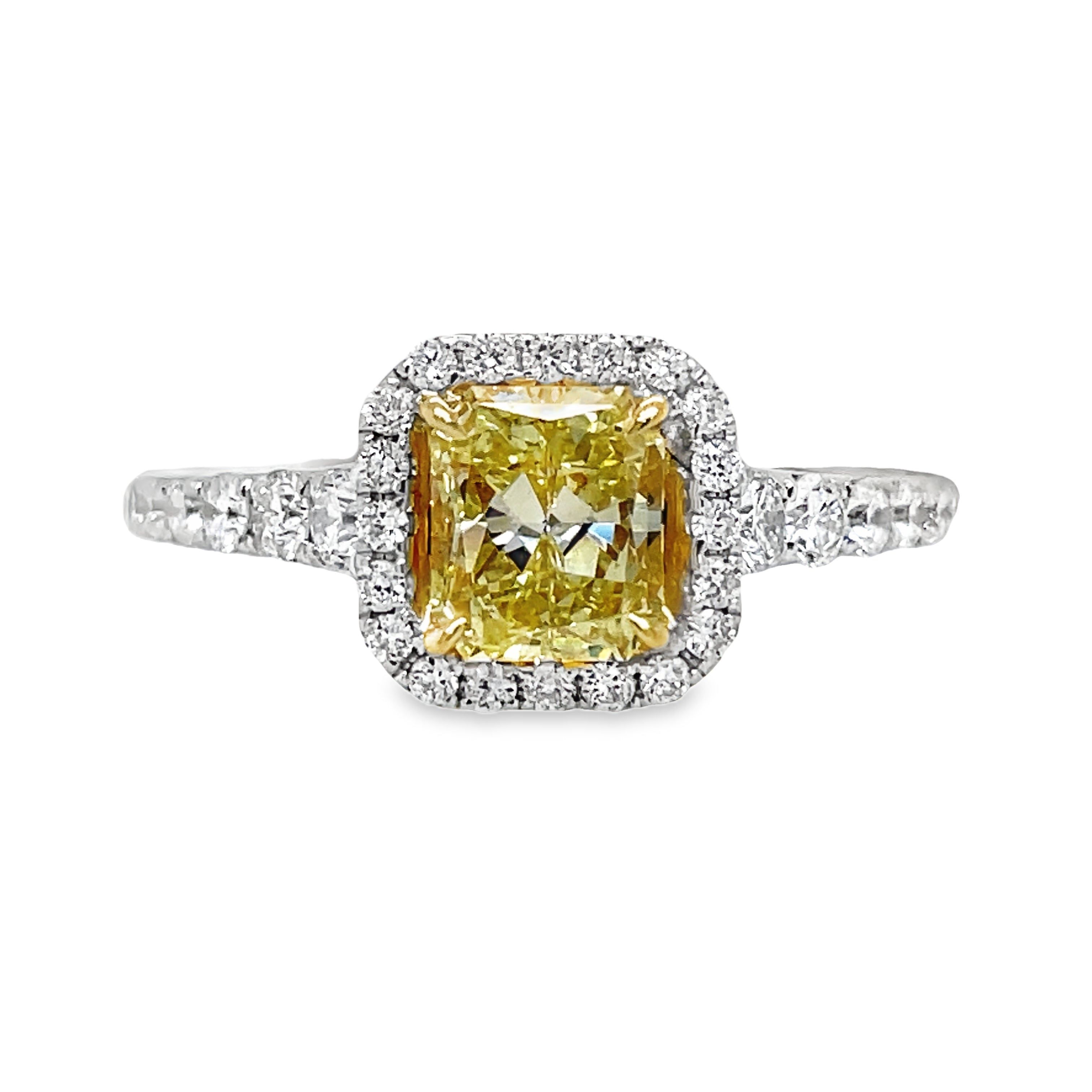 Indulge in the exquisite beauty of our custom-made Fancy Yellow Diamond Radiant Engagement Ring. Crafted from 18k white gold, this sophisticated ring features a stunning 1.10 carat radiant cut diamond surrounded by a 1.00 carat diamond halo and along the shank. The diamonds are set inside the ring, adding to its exclusive design. Elevate your engagement with this luxurious piece.