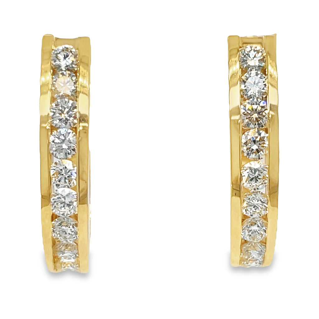 These oval shape gold bezel hoop earrings feature 1.50 ct round diamonds of F/G color and VS1 clarity. The hoops are 4.50 mm thick and 1" long, crafted from 14k yellow gold with a secure omega clasp. Lever back system ensures the earrings are easy to put on and take off.