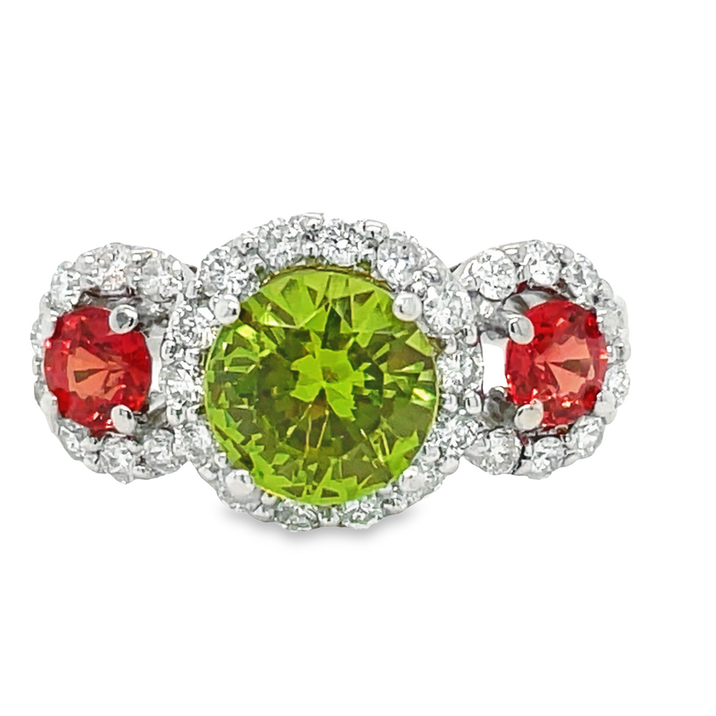 This stunning three-stone ring features a round peridot center stone, two orange sapphire side stones surrounded with 0.60 cts of round diamonds. The combination of these three gemstones make this classic ring a unique and eye-catching piece.