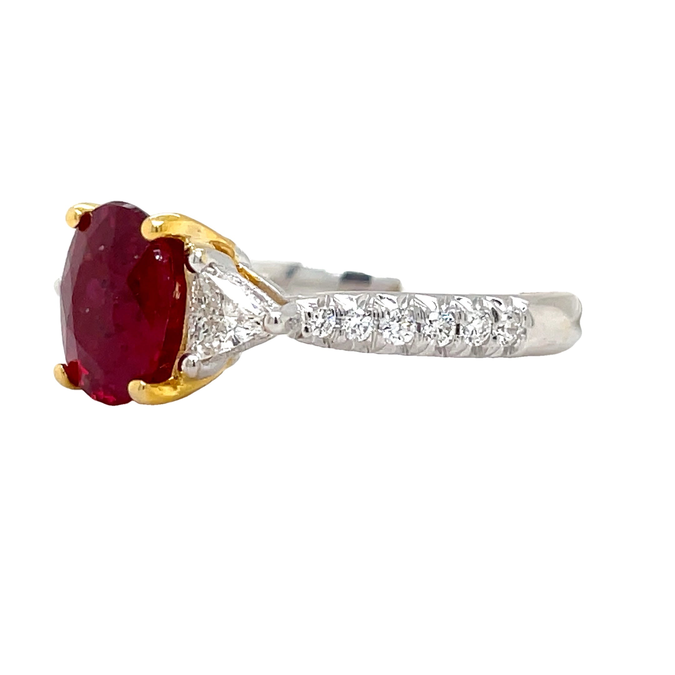 Indulge in luxury with our Oval Madagascar Ruby and Trillion Diamond Ring. This exquisite piece features a stunning oval ruby from Madagascar, weighing 1.71 carats, surrounded by 0.58 carats of round diamonds set in 18k white gold. The perfect combination of sophistication and opulence, with yellow gold prongs and head adding a touch of elegance.