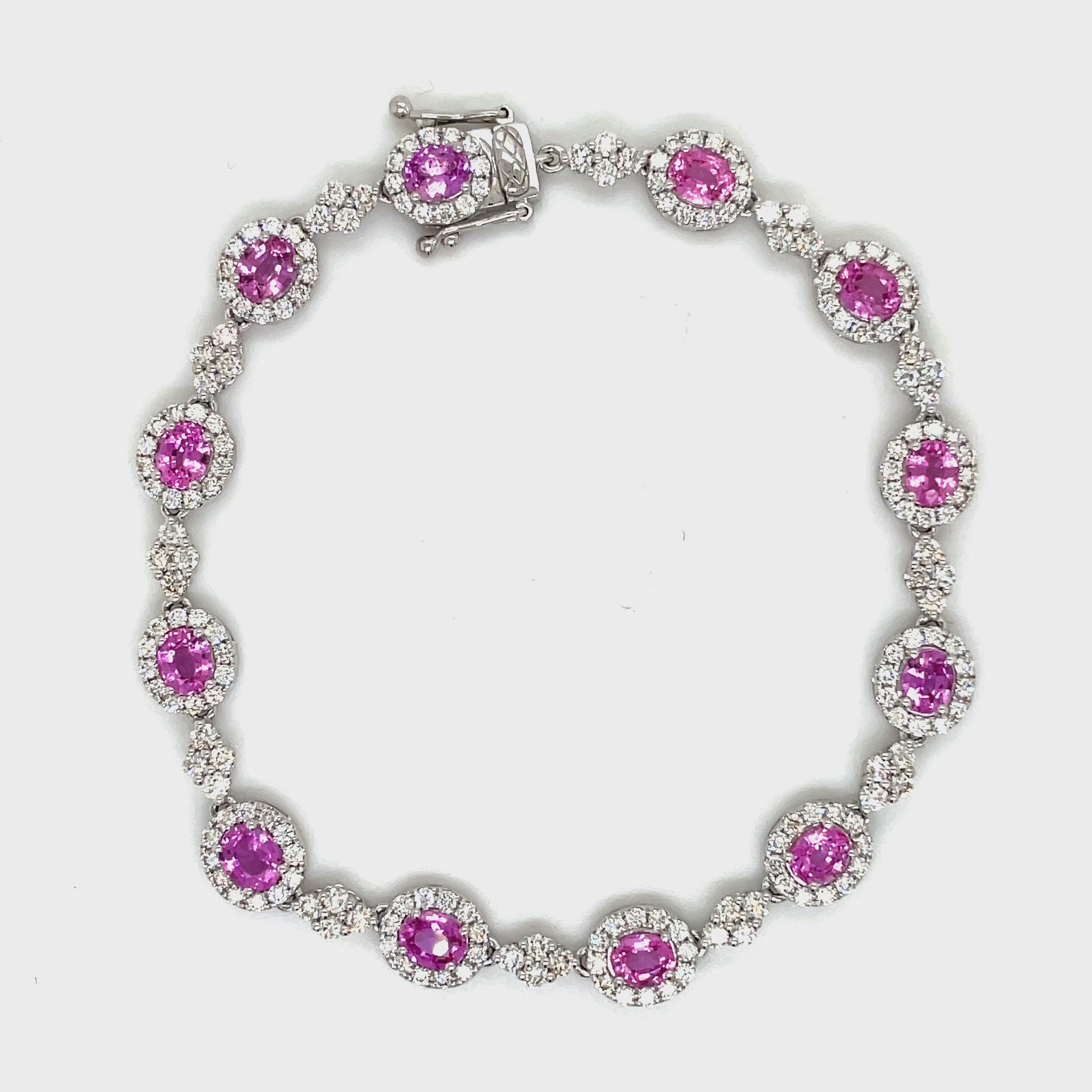 This exquisite bracelet features a 5.53 carat oval pink sapphire and 3.29 carats of dazzling round diamonds set in 18k white gold. With a sleek 7.5" length and hidden clasp, this luxurious piece is the epitome of elegance and sophistication. Add a touch of glamour to any outfit with this stunning Pink Sapphire &amp; Diamond Bracelet.