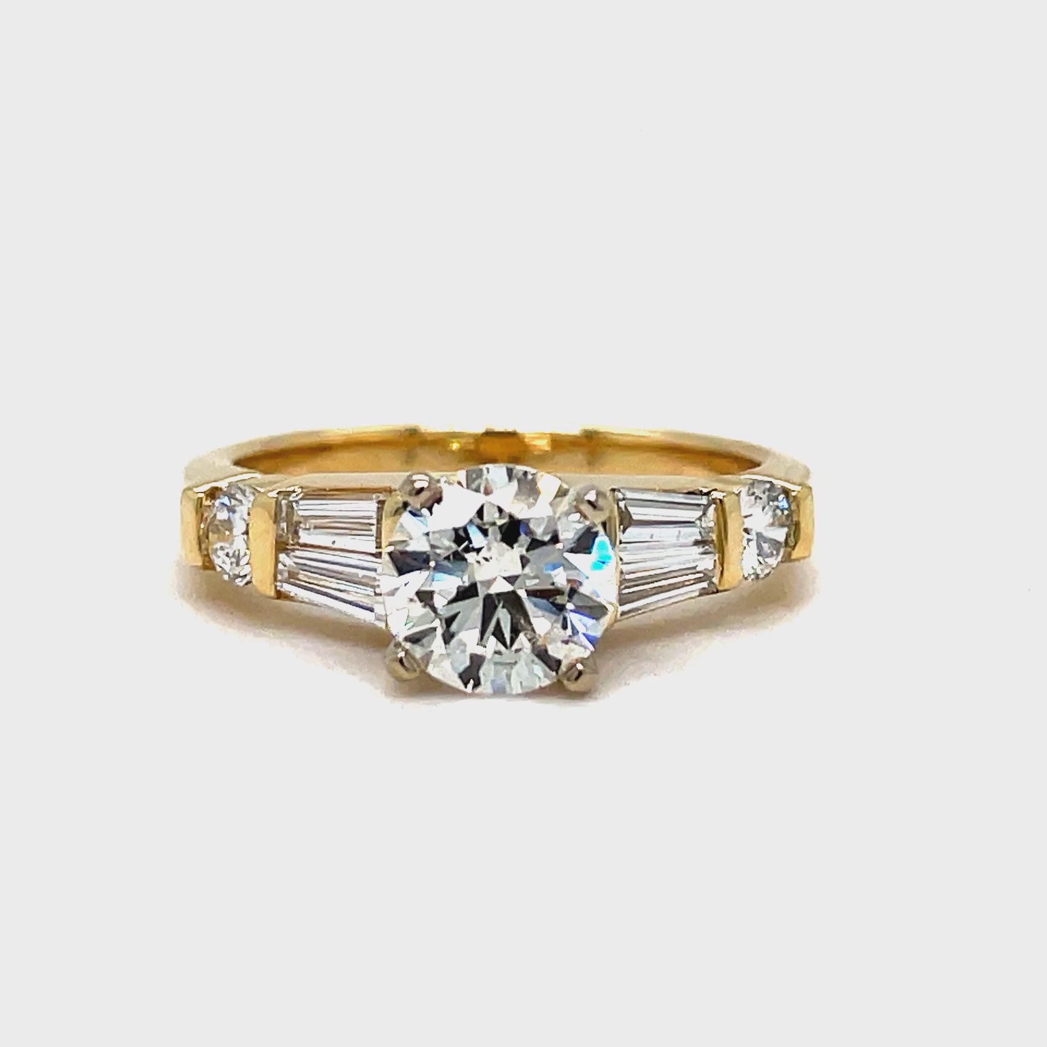 ndulge in luxury with this Round Brilliant Diamond &amp; Baguette Engagement Ring. With a striking 1.02 ct round brilliant diamond, framed by tapered baguette diamonds and two small round diamonds totaling 0.40 cts, this exquisite ring exudes elegance and sophistication. Crafted in 14k yellow gold, it's the perfect symbol of your love.