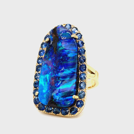 Indulge in elegance with our Hand Made Large Australian Black Opal and Sapphire Ring. Crafted with 14k yellow gold, the stunning 18.00 ct opal boasts a mesmerizing play of color. Adorned with 3.00 ct round sapphires, this piece is a true work of art.