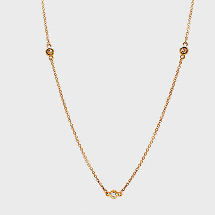 ndulge in the timeless elegance of our Diamond by the Yard Necklace. Adorned with a 5 brilliant 0.25 carat round diamond total securely bezel set in 14k yellow gold, this necklace exudes luxury and sophistication. The 18" chain is finished with a secure lobster catch, making it the perfect addition to any outfit. Elevate your style with this stunning piece today!