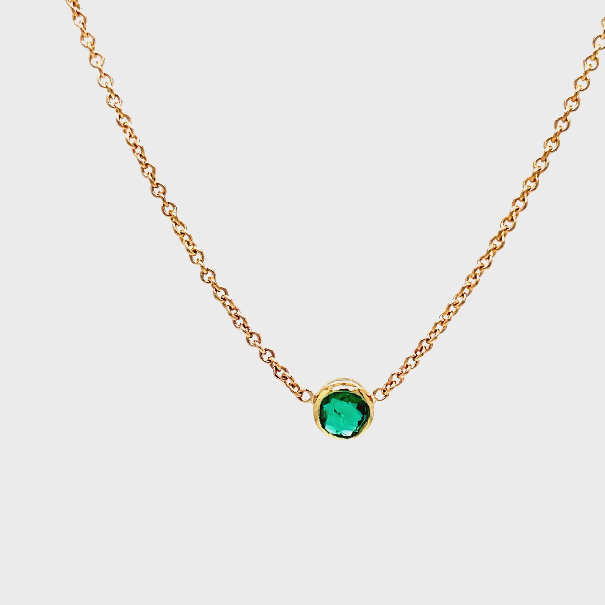 dulge in the exquisite elegance of our Small Colombian Round Emerald Necklace. The dainty 14k yellow gold chain delicately showcases a stunning round emerald, evoking luxury and sophistication. With a secure lobster clasp, this 16" necklace is the perfect choice for a touch of timeless beauty.