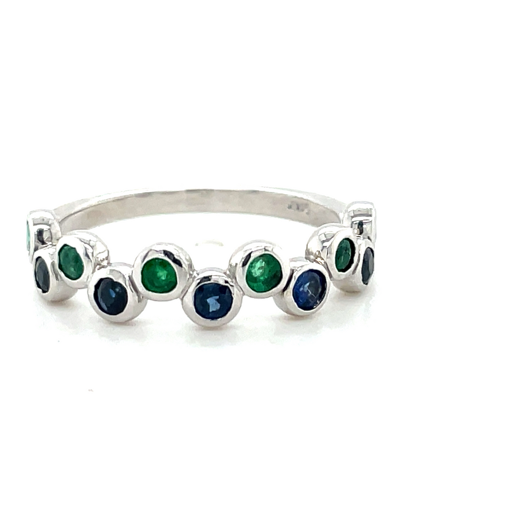 Custom made for our 40th anniversary.  This ring is to resemble the peacock color of our store logo.  Round Colombian emeralds 0.25 cts  Round Tanzanites 0.25 cts   Set bezel set   5.20 mm   Size 6.5 (sizeable)