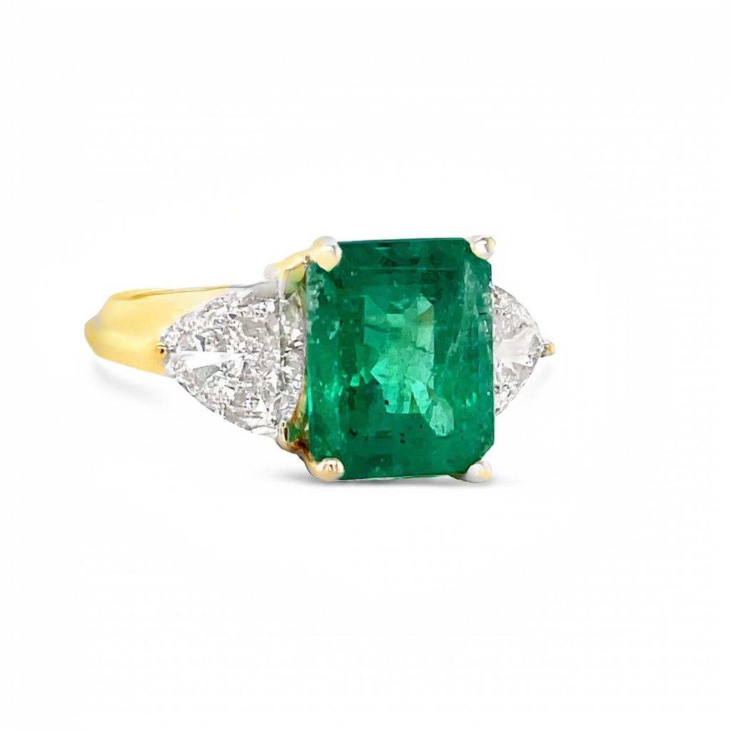 This stunning Muzo Mines emerald, boasting a 3.00 carat emerald cut, is the centerpiece of this 18k yellow gold ring. Accompanying it are two trillion cut diamonds weighing 1.30 carats, and the band measures 10.00 millimeters in width.