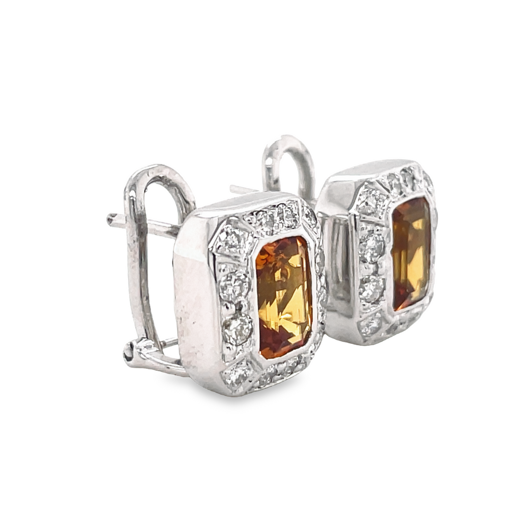 The Bezel Set Citrine Diamond Earrings offer sparkling style with 1.80 carats of round diamonds, emerald-cut citrine gems and 14k white gold. Finished with secure omega clips and a gallery finish of 14.00 mm, these earrings are a timeless addition to any jewelry collection.