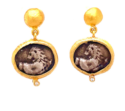 Crafted in Turkey, these earrings are designed with a 21 mm long secure post. Made of 24K yellow gold and oxidized sterling silver, each earring is adorned with a small round diamond. On the front side is a Pegasus design, which symbolizes righteousness, while the back side contains a prehistoric design.