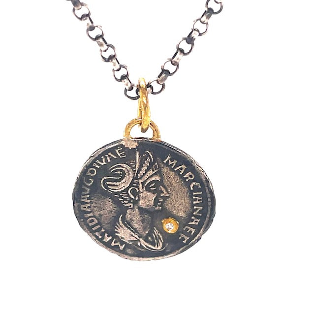 This exquisite piece features a classic 19.00mm round coin crafted from 24k gold with a matte finish and delicately detailed with a small round diamond. The optional necklace ($90) is handmade from the highest quality Turkish materials and includes an oxidized sterling silver chain with a secure lobster clasp closure. 