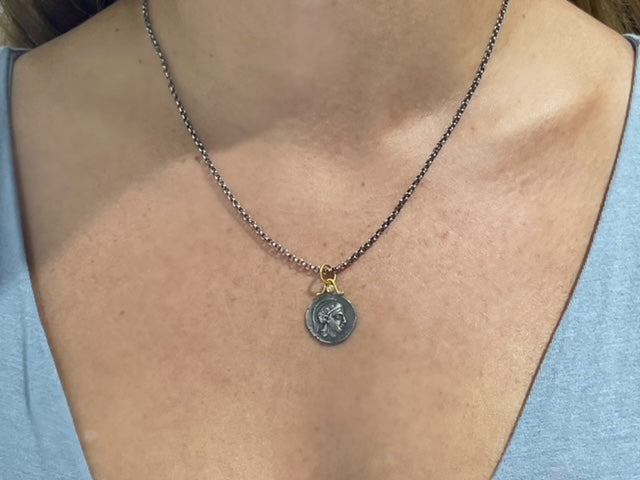 This 15.50 mm Athena pendant is crafted with a round coin-like style, featuring a small round diamond, 24k gold and a matte finish. Handmade in Turkey, it can be paired with an optional oxidized sterling silver chain with secure lobster catch, measuring 20" long ($90). 