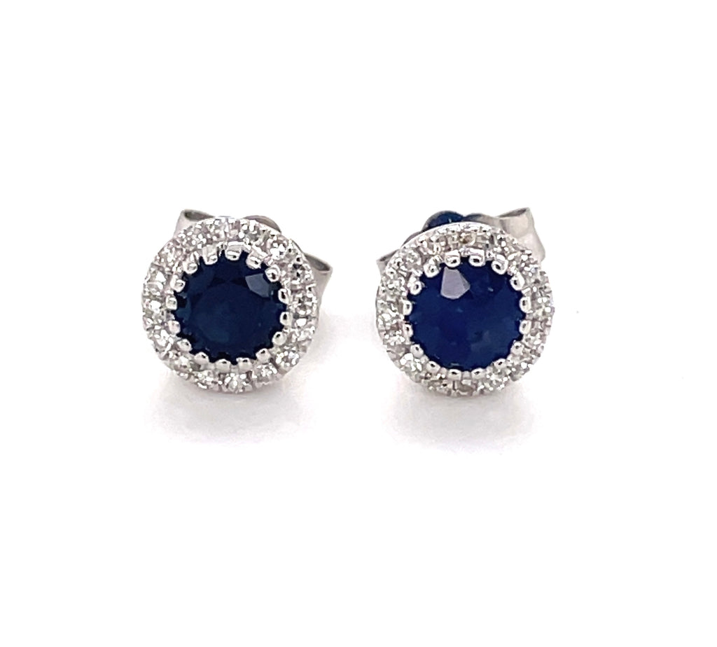 This pair of earrings features a blue sapphire center of 0.81 carats, enhanced by 0.11 carats of round white diamonds. The stones are set in a 14K white gold bezel setting and are secured with friction backs measuring 6.50 mm.