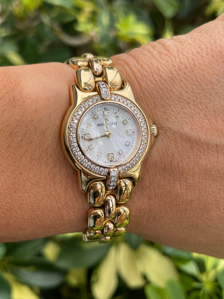 This Bertolucci Diamond Vir 18k yellow gold watch features a 0.55 ct round diamonds on its MOP dial, as well as quartz movement and a stainless steel link bracelet fastened with a deployment buckle. Hour markers are also present in diamond.