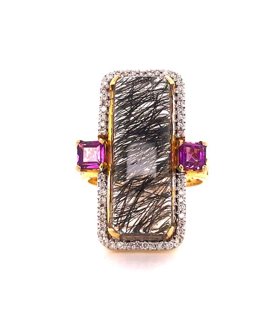 One rectangular cabochon rutilated quartz 27.50 x 10.00 mm 11.45 cts  Bezel set round diamonds 0.27 cts   Square pink garnets 0.95 cts  Set in 14k yellow gold  Gallery finish on side of the band