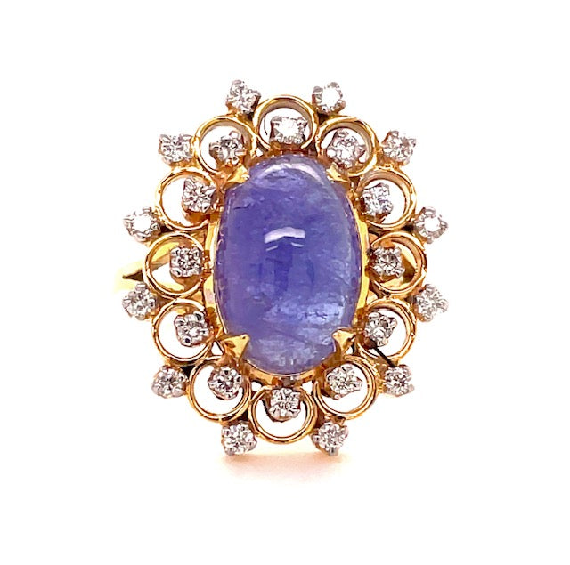 One round tanzanite cabochon 14.00 x 10.00 mm 5.80 cts  Crowned with a diamond gallery around the tanzanite  Round diamonds 0.48 cts  Set in 14k yellow gold  Open shank yellow band