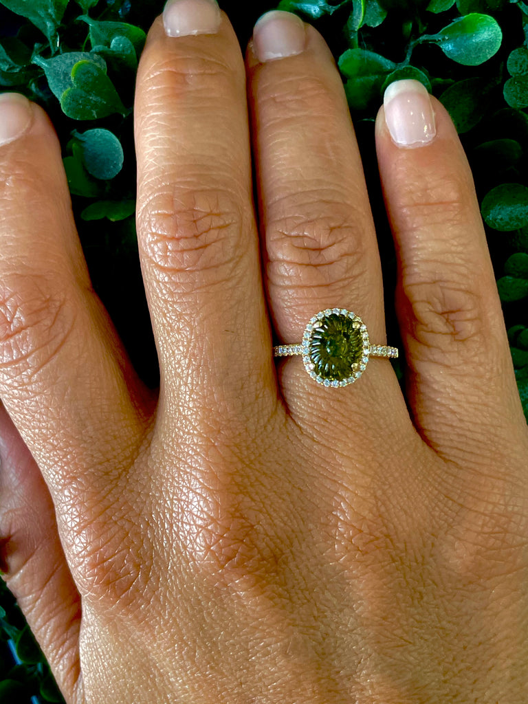 This stunning Carved Oval Green Tourmaline Diamond Halo Ring is crafted from 14k yellow gold and features a round green tourmaline encircled by 0.45 cts of white round diamonds. Size 6.5 and 11.00 mm.