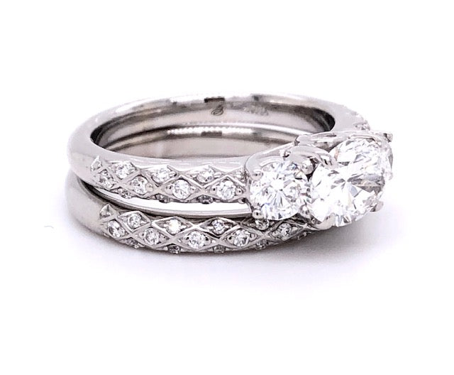 This eye-catching East-West setting has seen a surge in popularity, and for good reason! It elevates the beauty of your wedding band while offering all-day comfort. Combining a modern GIA certified 0.98 ct Oval cut, Color F, Clarity SI2 diamond with a contemporary 18k white gold mounting adorned with two round side diamonds totaling 0.40 cts and a matching filigree style 18k white gold band totaling 0.90 cts; it's luxury that's simply to die for.