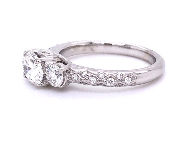 This eye-catching East-West setting has seen a surge in popularity, and for good reason! It elevates the beauty of your wedding band while offering all-day comfort. Combining a modern GIA certified 0.98 ct Oval cut, Color F, Clarity SI2 diamond with a contemporary 18k white gold mounting adorned with two round side diamonds totaling 0.40 cts and a matching filigree style 18k white gold band totaling 0.90 cts; it's luxury that's simply to die for.