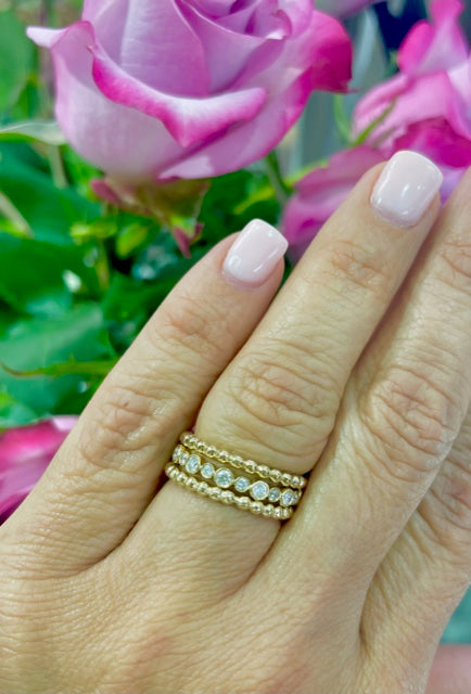 A luxurious 14k yellow gold setting showcases sparkling round diamonds of 0.50 cts, expertly bezel set! Stack this beauty together for a dazzling look!